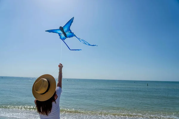 Stock image A beautiful mature brunette model enjoys a day at the beach while flying her kite near the shore