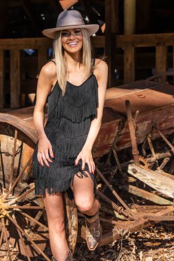 A gorgeous blonde cowgirl model poses outdoors while enjoying the spring weather