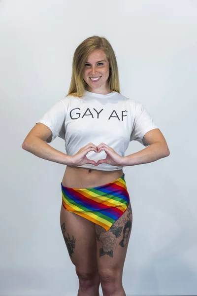 stock image Studio image of happy young blonde LBGTQ woman wearing rainbow colored clothes smiling at camera.  Concept of homophobia, diversity, equity, peace and love, freedom, liberty. LGBT rights concept.  