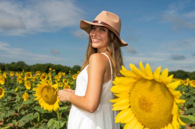 A gorgeous blonde model poses outdoors in a field of sunflowers