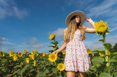 Sarışın bir model, ayçiçeği tarlasında poz veriyor.