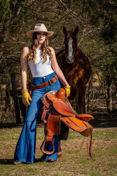 一个漂亮的黑发女牛仔骑着马到乡下去之前摆姿势 — 图库照片