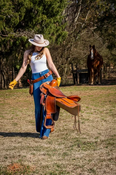 一个漂亮的黑发女牛仔骑着马到乡下去之前摆姿势 — 图库照片