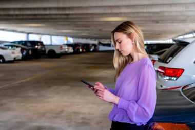 Muhteşem sarışın bir model başarılı bir toplantıdan sonra kapalı otoparkta arabasına doğru yürür.