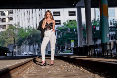 Sarışın bir model gün batımında tren raylarında poz veriyor.