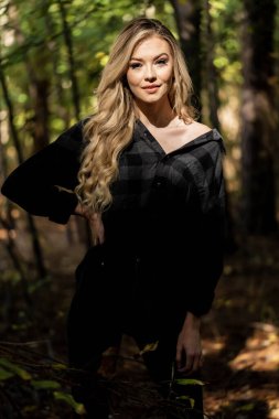 Muhteşem sarışın bir model, kasvetli bir orman ortamında poz veriyor.