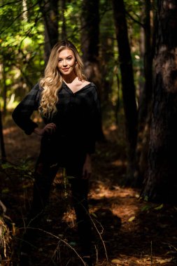 Muhteşem sarışın bir model, kasvetli bir orman ortamında poz veriyor.