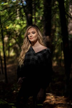 Muhteşem sarışın bir model, kasvetli bir orman ortamında poz veriyor.