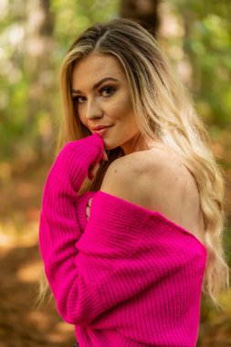 Muhteşem sarışın bir model, kasvetli bir orman ortamında poz veriyor.