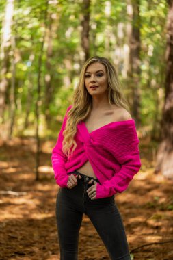 Muhteşem sarışın bir model, kasvetli bir orman ortamında poz veriyor.