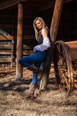 A gorgeous blonde cowgirl model poses outdoors while enjoying the spring weather