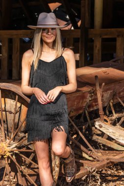 A gorgeous blonde cowgirl model poses outdoors while enjoying the spring weather