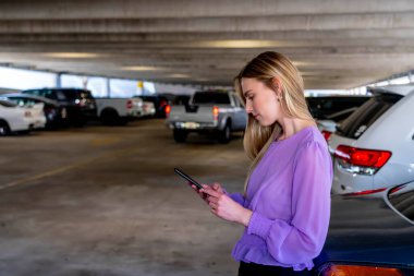 Muhteşem sarışın bir model başarılı bir toplantıdan sonra kapalı otoparkta arabasına doğru yürür.
