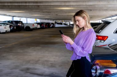 Muhteşem sarışın bir model başarılı bir toplantıdan sonra kapalı otoparkta arabasına doğru yürür.