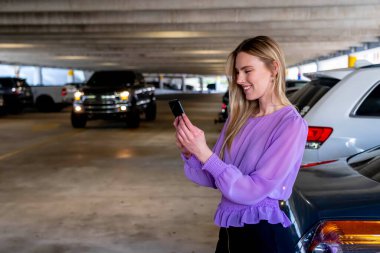 Muhteşem sarışın bir model başarılı bir toplantıdan sonra kapalı otoparkta arabasına doğru yürür.