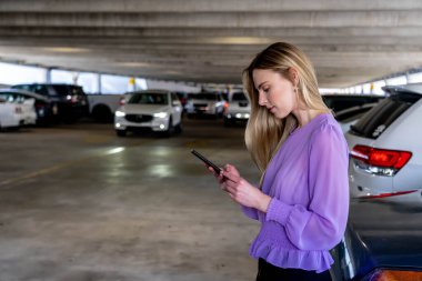Muhteşem sarışın bir model başarılı bir toplantıdan sonra kapalı otoparkta arabasına doğru yürür.