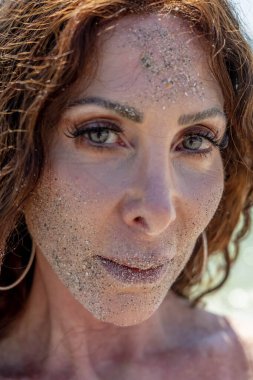 Güzel, olgun bir esmer model kumsalda güzel bir günün tadını çıkarıyor.