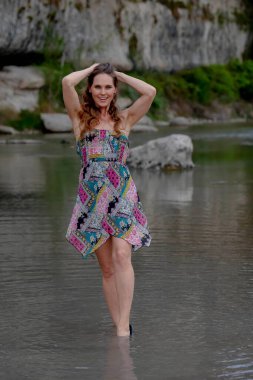 Muhteşem bir esmer model göl kenarındaki yaz havasının tadını çıkarıyor.