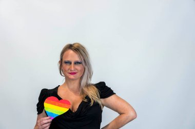 Studio image of happy young blonde LBGTQ woman wearing rainbow colored clothes smiling at camera.  Concept of homophobia, diversity, equity, peace and love, freedom, liberty. LGBT rights concept.  