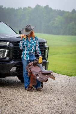 Güzel bir kızıl saçlı model, kovboy kız kıyafeti giyerek bir ülkede poz veriyor..