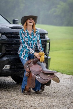 Güzel bir kızıl saçlı model, kovboy kız kıyafeti giyerek bir ülkede poz veriyor..