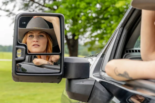 美しい赤毛モデルは彼女の農場でカウボーイの帽子をかぶっている間彼女のトラックに座っています — ストック写真