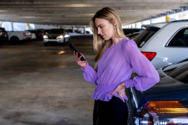 Muhteşem sarışın bir model başarılı bir toplantıdan sonra kapalı otoparkta arabasına doğru yürür.