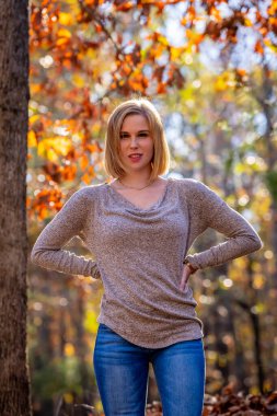 Muhteşem bir sarışın model açık havada sonbahar havasının tadını çıkarıyor.