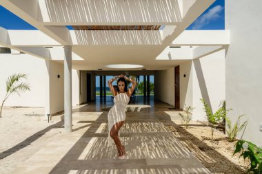 Muhteşem bir Latin model bambu tavanının altında poz veriyor, fayans zeminde güzel şekiller yapıyor..