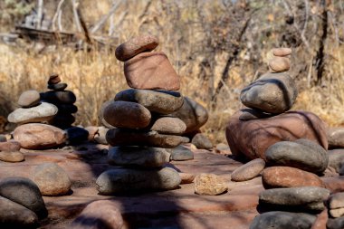 Güneşli bir günde Arizona çölünde dengeli çakıl taşı piramidi. Arka planda soyut bokeh. Seçici odaklanma. Deniz sahilinde Zen Taşları, meditasyon, spa, uyum, sakinlik, denge konsepti