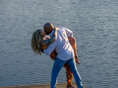 Genç bir ırklar arası çift, dışarıda güzel bir yaz gününde nişan fotoğrafları için poz veriyor.