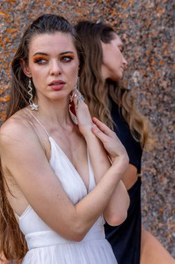 İki çarpıcı model, doğadaki zengin duvar halısı ve güzelliğin ortasında poz veriyor..