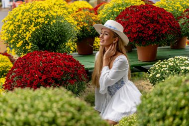 Güzel bir Avrupalı sarışın kadın, önümüzdeki sonbahar festivalleri için bazı çiçeklerin fotoğrafını çekiyor.