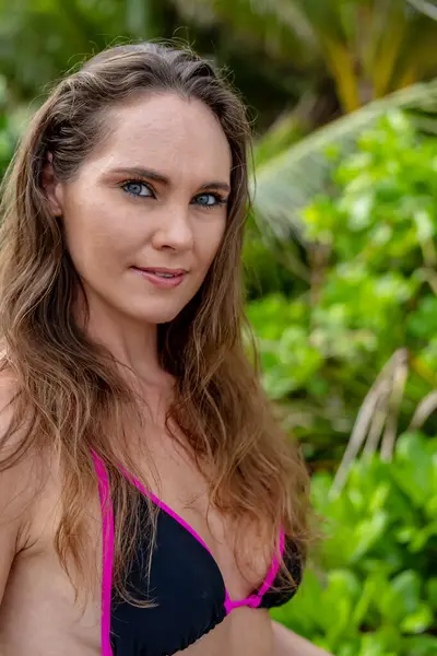 Bikinili, güneşli esmer, kumlu sahillerde Karayipler 'de eğleniyor, güzelliği macera ile birleştirerek hindistan cevizi avlıyor.