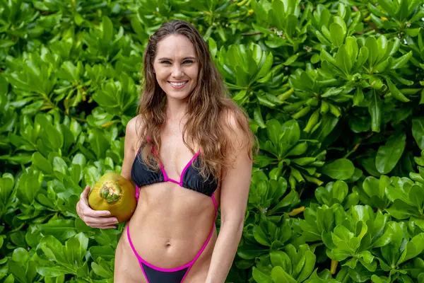 Bikinili, güneşli esmer, kumlu sahillerde Karayipler 'de eğleniyor, güzelliği macera ile birleştirerek hindistan cevizi avlıyor.