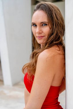 Göz kamaştırıcı esmer, canlı kırmızı bir elbise içinde ışıl ışıl, Karayip kıyılarını zarafetle süslüyor, tropik cennetin ortasında güzelliği somutlaştırıyor.