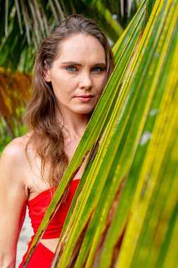 Göz kamaştırıcı esmer, canlı kırmızı bir elbise içinde ışıl ışıl, Karayip kıyılarını zarafetle süslüyor, tropik cennetin ortasında güzelliği somutlaştırıyor.