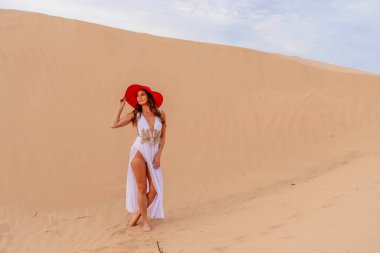 Zarif model kum tepelerindeki doğanın güzelliğini kucaklıyor, engin, doğal ihtişamın arkaplanına karşı zarafeti simgeliyor.