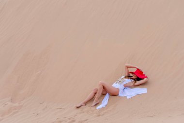 Zarif model kum tepelerindeki doğanın güzelliğini kucaklıyor, engin, doğal ihtişamın arkaplanına karşı zarafeti simgeliyor.