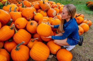 Güzel bir Avrupalı sarışın kadın yaklaşan sonbahar festivalleri için balkabağı ve çiçek fotoğrafı çekiyor.