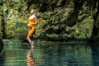 In Cuzama, Yucatan, Mexico, a stunning model revels in the vibrant hues of a cenote's blue and green waters, creating a picturesque scene of natural beauty. clipart