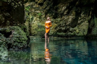 In Cuzama, Yucatan, Mexico, a stunning model revels in the vibrant hues of a cenote's blue and green waters, creating a picturesque scene of natural beauty. clipart