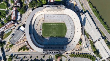 An aerial view of Neyland Stadium reveals a massive, iconic structure nestled by the Tennessee River, with its distinctive bowl shape and seating for over 100,000 fans, showcasing its rich football heritage. clipart