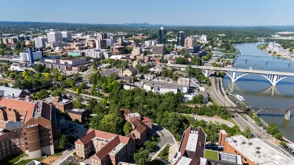 stock image An aerial view of Knoxville, Tennessee reveals a vibrant cityscape with a mix of historic and modern buildings, the Tennessee River weaving through downtown, lush green parks, and the distant Smoky Mountains framing the horizon.