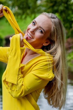 Parktaki şelalenin yanında çarpıcı sonbahar kıyafetleri içinde parlayan sarışın güzellik, güzel bir sonbahar sahnesi..