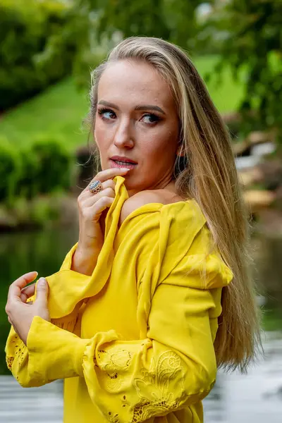 stock image Blonde beauty shines in stunning fall attire near park waterfall, a picturesque autumn scene.