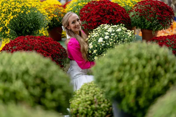 Güzel bir Avrupalı sarışın kadın, önümüzdeki sonbahar festivalleri için bazı çiçeklerin fotoğrafını çekiyor.