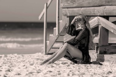 Güzel sarışın bir bikini mankeni sahilde açık havanın tadını çıkarıyor.