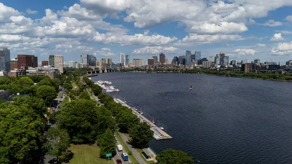 stock image From above the Charles River, Boston gleams under the summer sun. The skyline, with its mix of historic and modern architecture, contrasts with lush green parks, bustling streets, and the iconic bridges below.