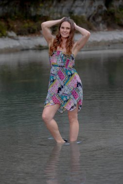 Muhteşem bir esmer model göl kenarındaki yaz havasının tadını çıkarıyor.